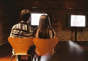 A couple watching a television screen together.