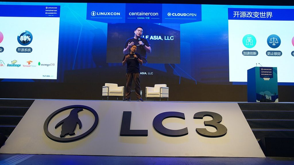 Speaker on stage at a large technology conference with presentation screens